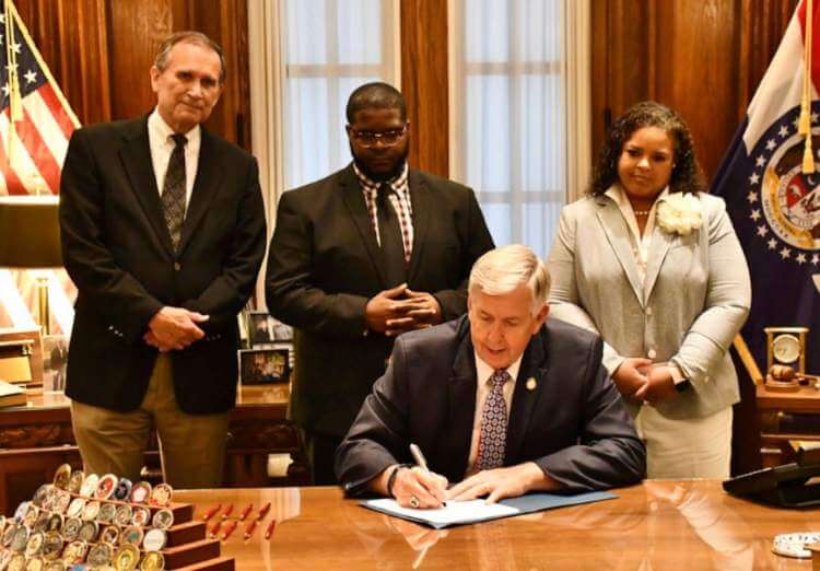 Photo of Governor Michael Parson signing SB203. Also pictures Paul M. Brown; Jason Groce, Chief of Staff for Senator Jamilah Nasheed (St. Louis); and Senator Nikki Curls (Kansas City)